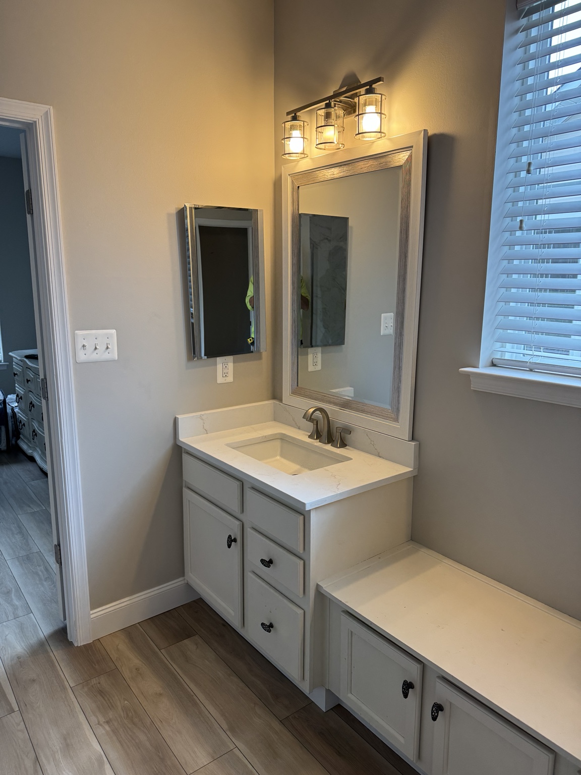 Finished bathroom vanity with wall mirror and sconce lighting